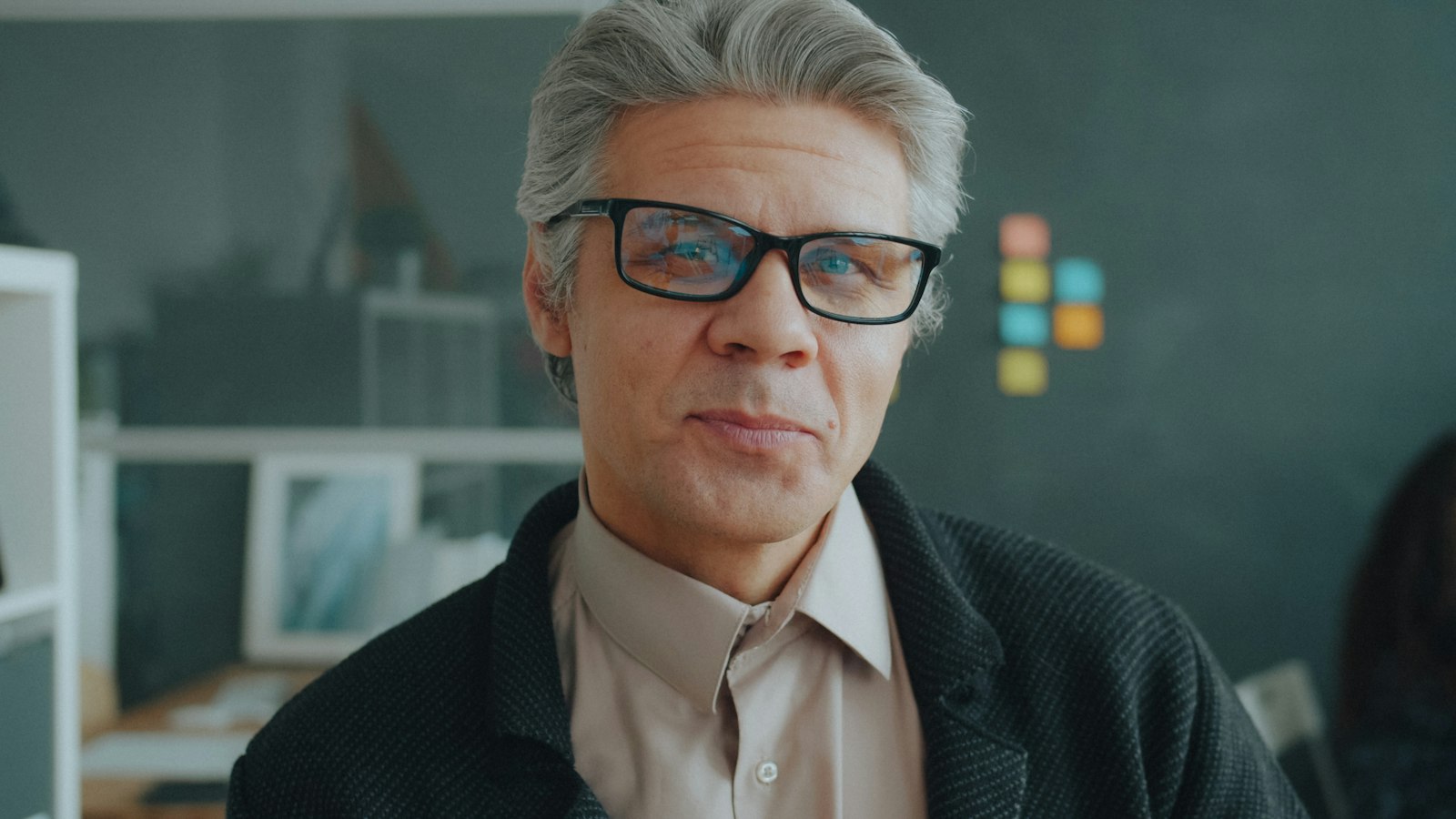 Un homme aux cheveux gris, à lunettes, dans un bureau